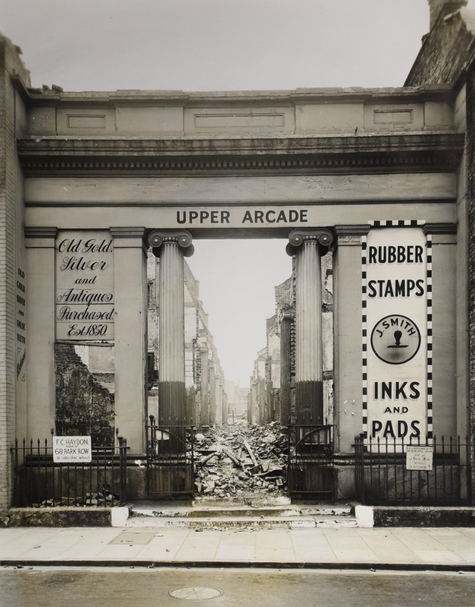 Black and white photograph, 11 cm x 15.6 cm, Upper Arcade entrance south elevation seen after bombing raid, Horsefare, City Centre, Bristol, nd, c 1940.