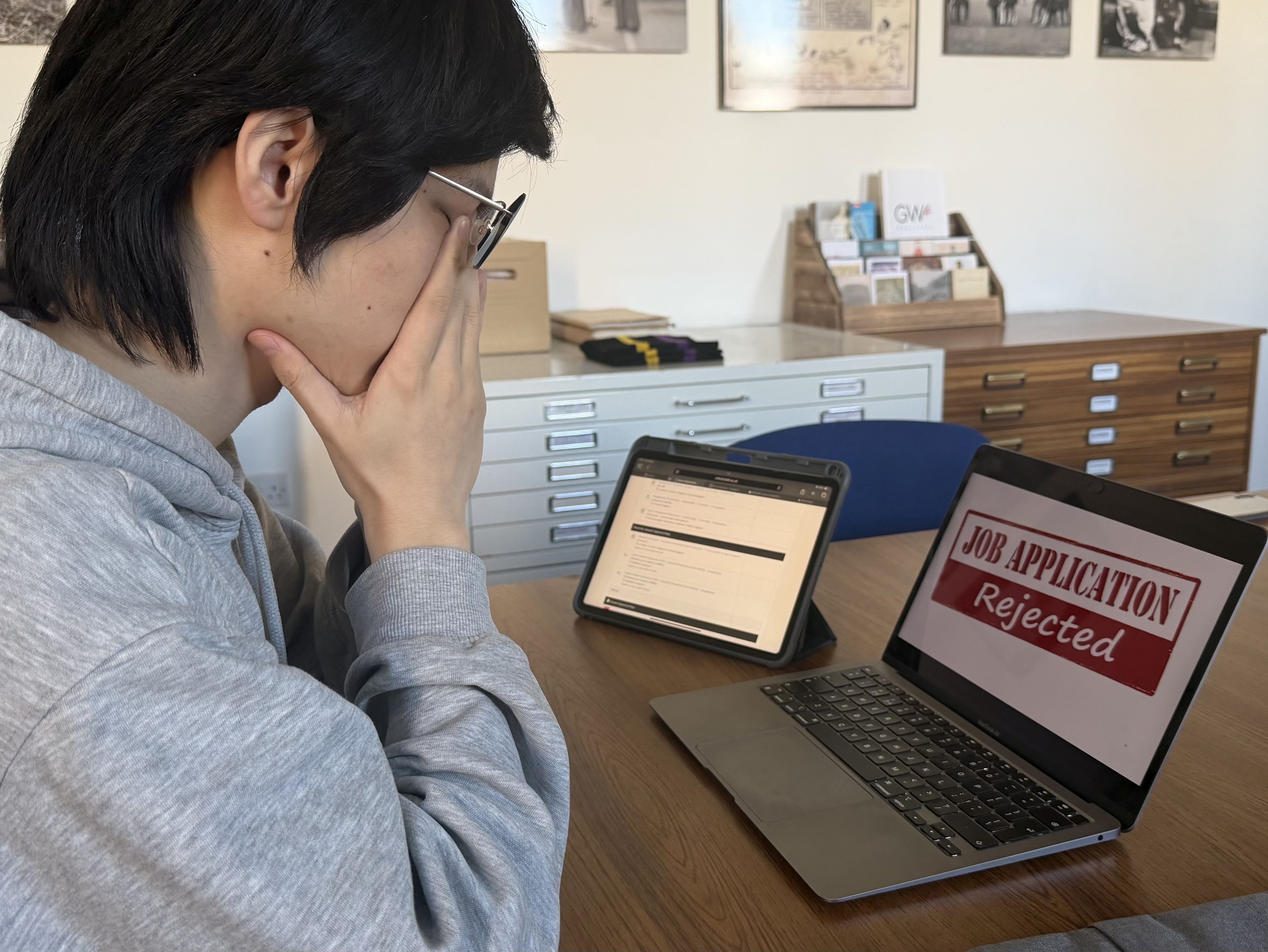 Photograph of a student looking at a laptop screen showing an electronic application rejection